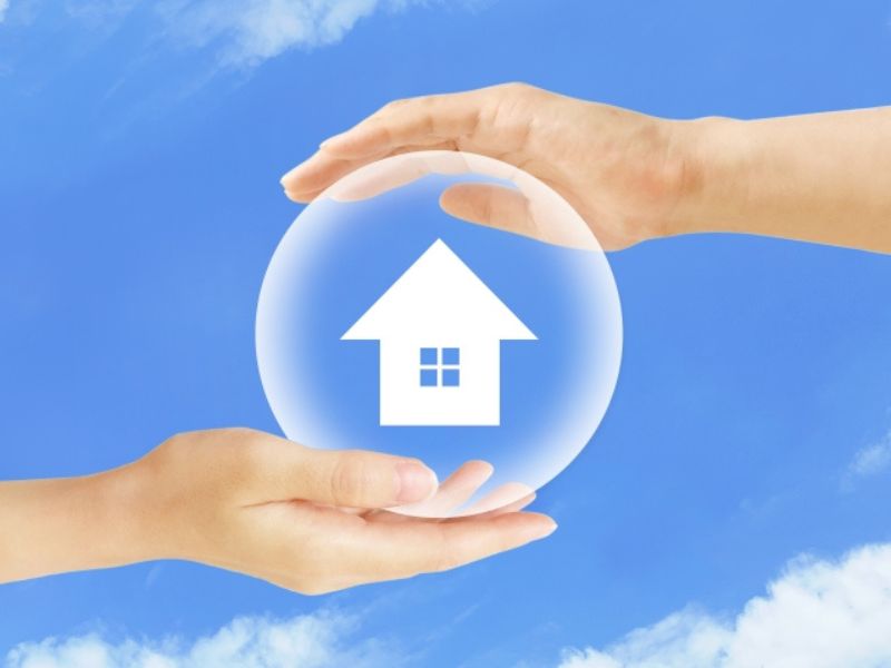 両手で大切に包み込まれた家のシルエット