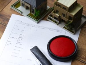 契約書類と朱肉と家の模型