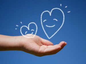 青空と手のひらの上に浮かぶ笑顔のハート